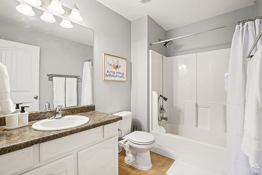 Bathroom with wood finished floors, vanity, and shower / tub combo with curtain