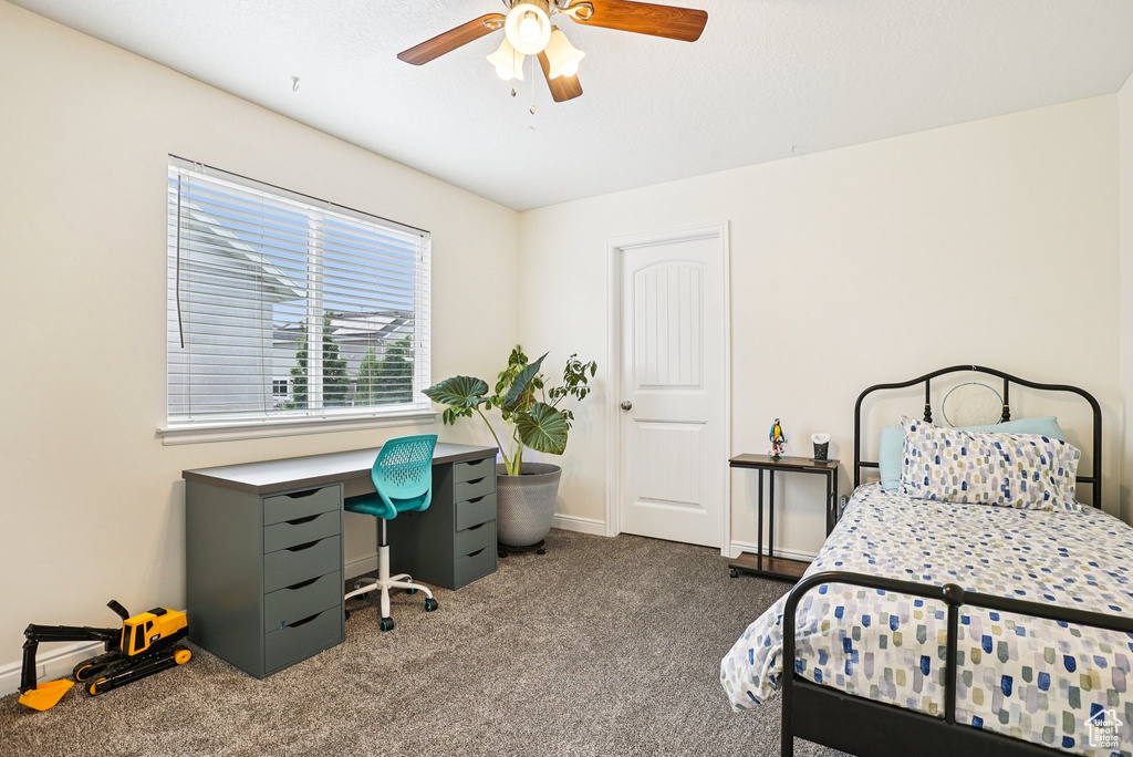 Carpeted bedroom featuring baseboards and ceiling fan