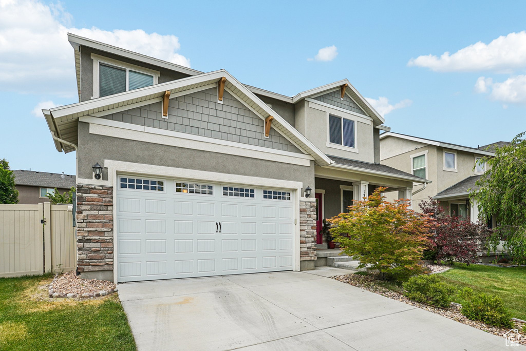 View of front of house featuring stone siding, stucco siding, driveway, and a gate
