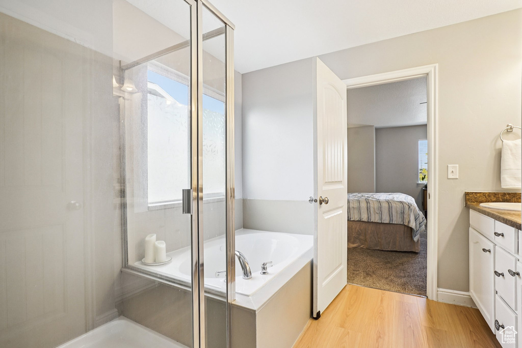 Bathroom with a shower stall, vanity, a garden tub, wood finished floors, and ensuite bathroom