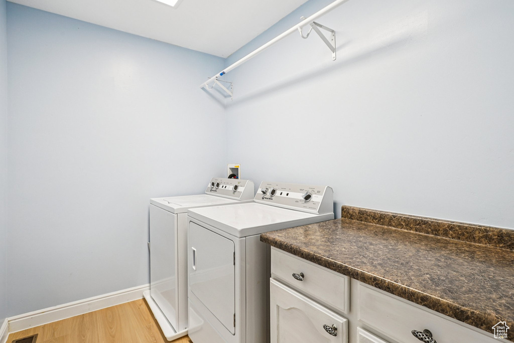 Washroom with washing machine and dryer and light wood-style floors