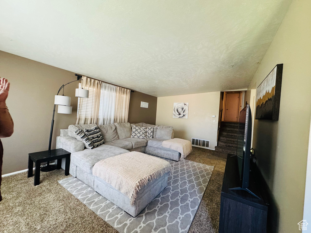 Living room featuring dark carpet, baseboards, and stairs