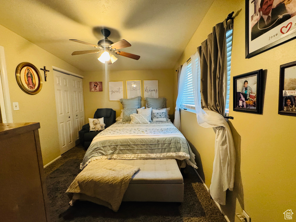 Bedroom with dark carpet, a ceiling fan, baseboards, and a closet