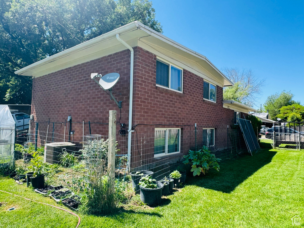 View of side of home featuring central AC, brick siding, a vegetable garden, and a greenhouse