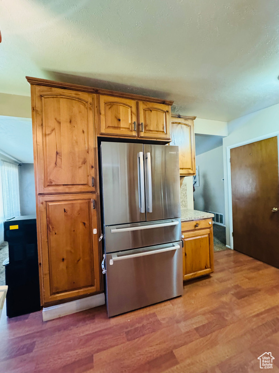 Kitchen featuring freestanding refrigerator, light wood finished floors, light countertops, and brown cabinetry