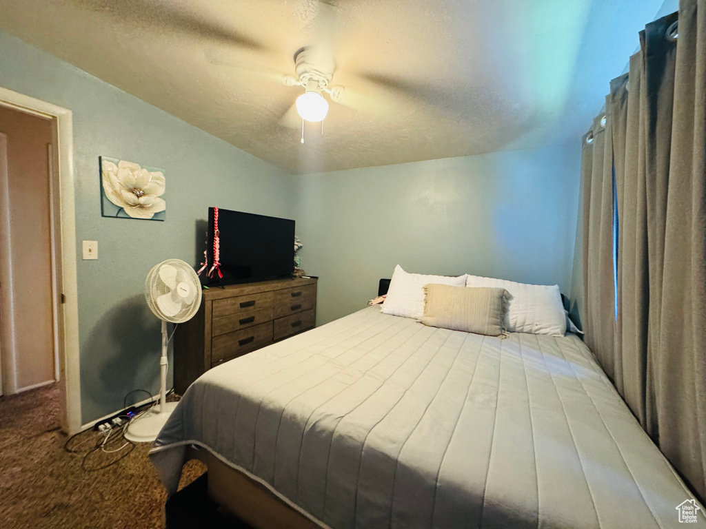 Carpeted bedroom with a ceiling fan and a textured ceiling