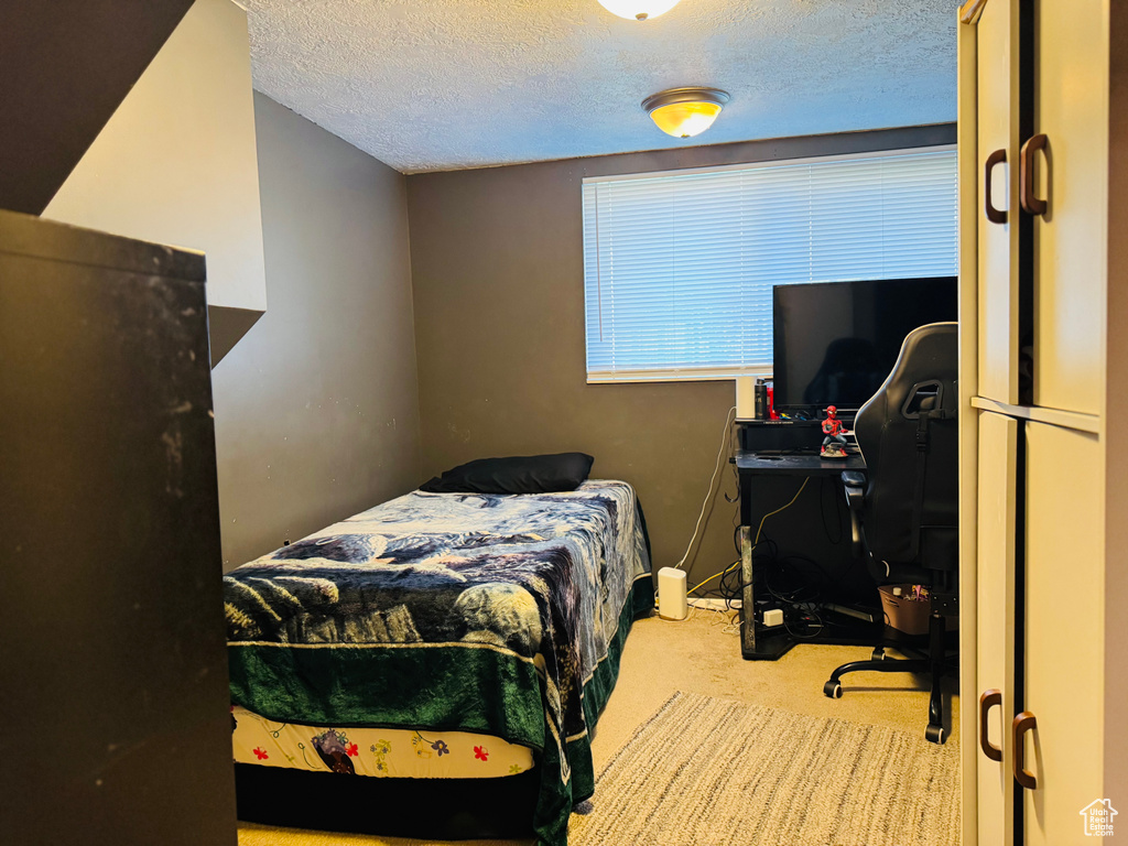 Bedroom with carpet floors, a desk, and a textured ceiling