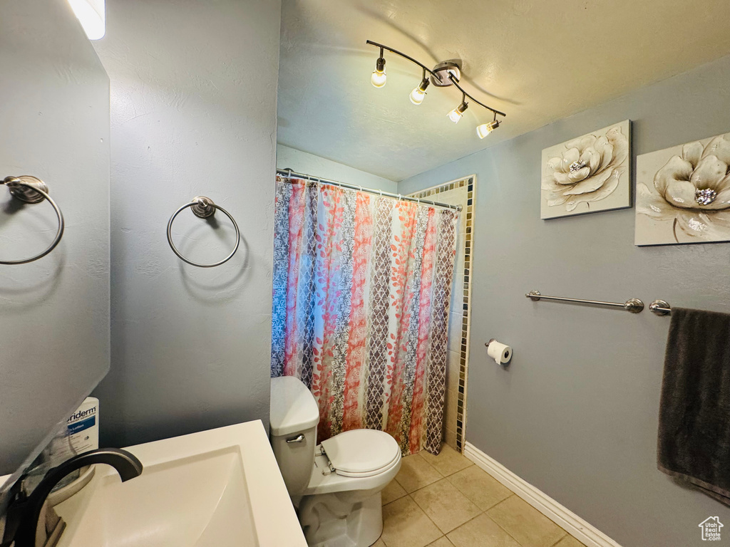 Full bath featuring tile patterned flooring, toilet, a sink, a shower with curtain, and baseboards