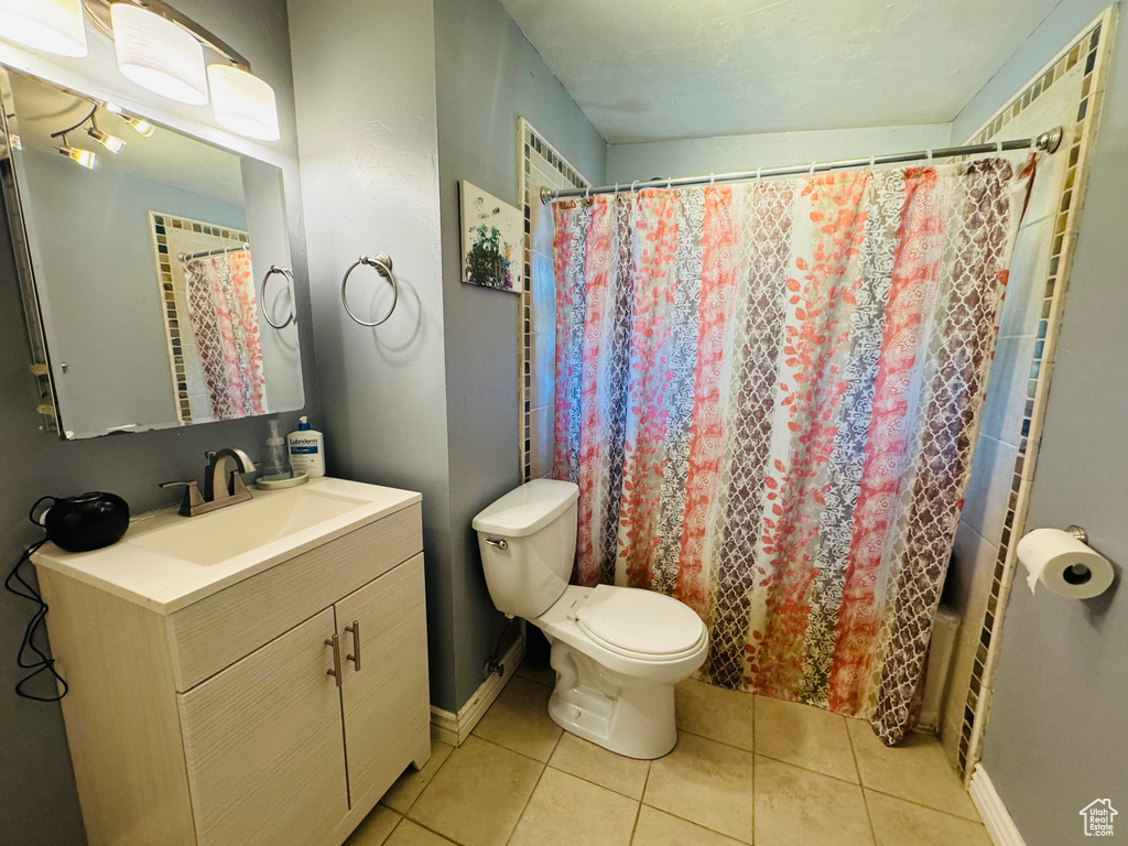 Bathroom with vanity, toilet, tile patterned flooring, and baseboards