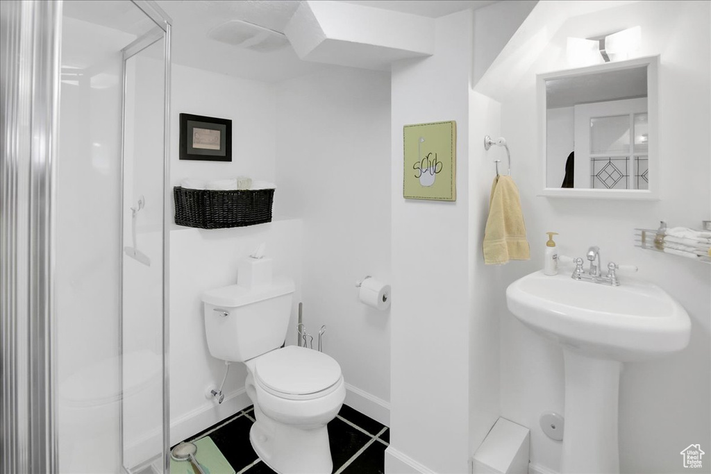 Full bathroom featuring a stall shower, toilet, tile patterned flooring, and baseboards