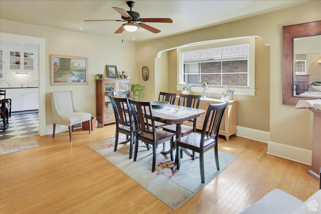 Dining area with light wood-style flooring, ceiling fan, baseboards, and arched walkways