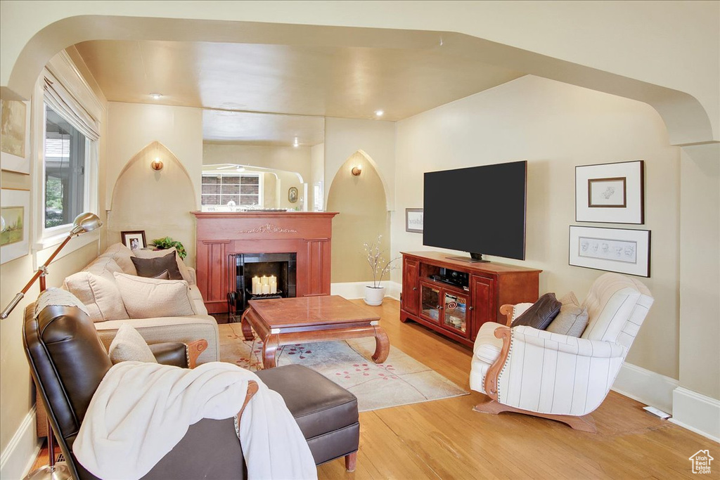 Living area with arched walkways, wood finished floors, a fireplace, and healthy amount of natural light