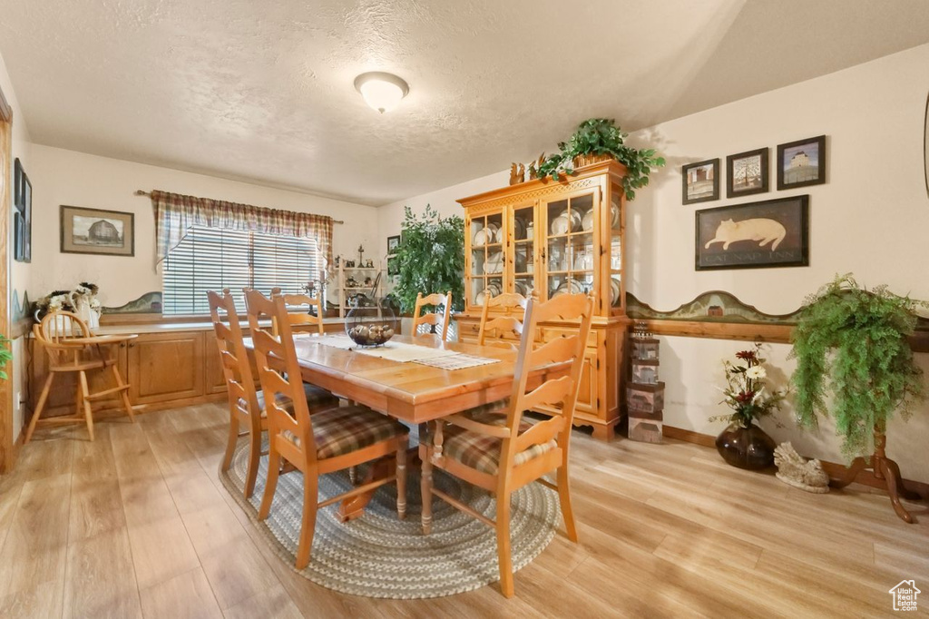 Dining room with light wood-style flooring, a textured ceiling, and baseboards