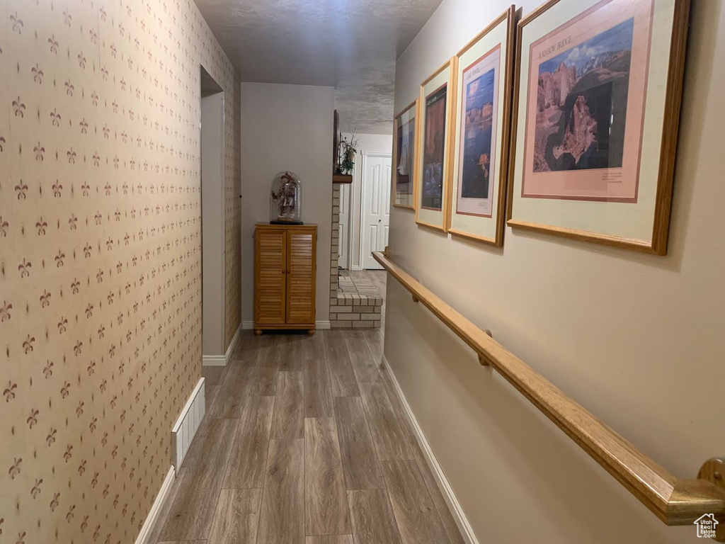 Hall with baseboards, wood finished floors, and wallpapered walls