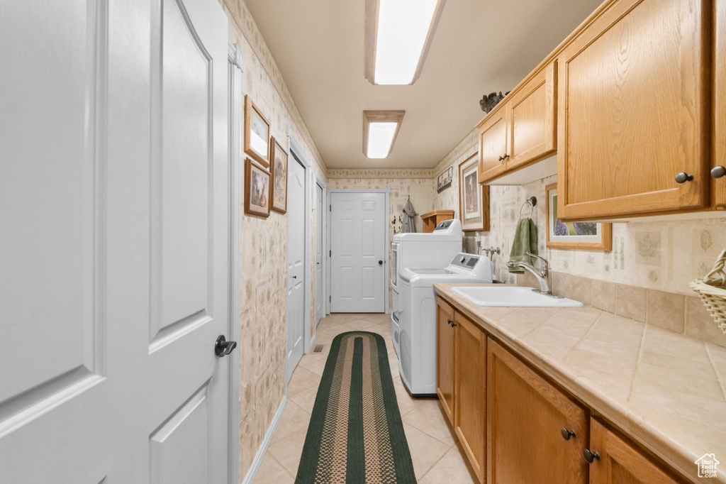 Washroom featuring washer and clothes dryer, cabinet space, light tile patterned floors, and wallpapered walls