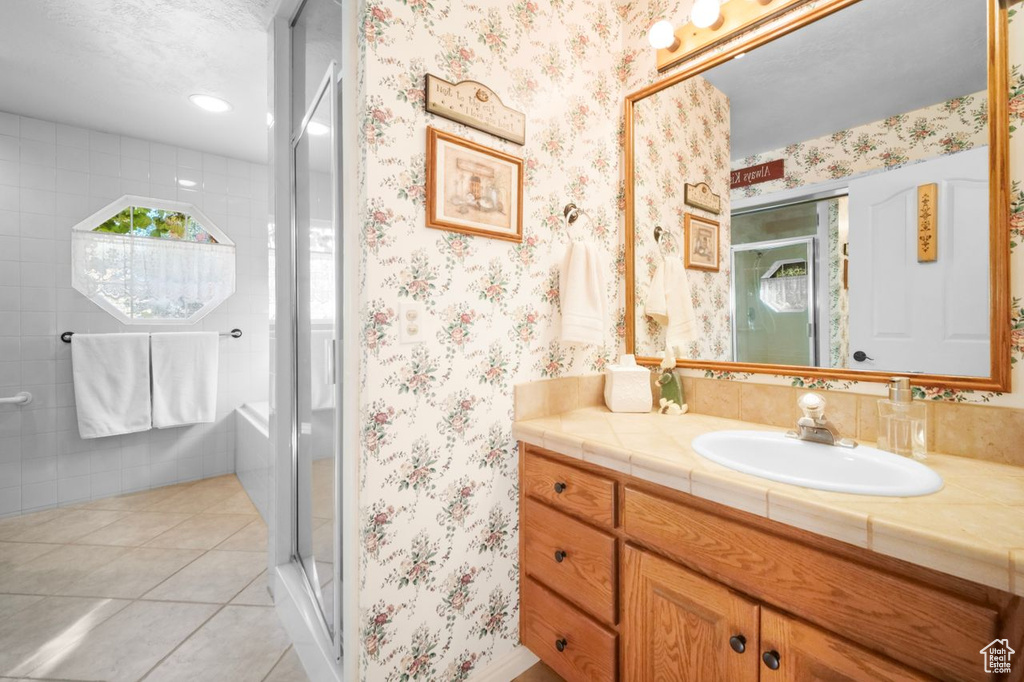 Full bath with vanity, a shower stall, wallpapered walls, and tile patterned flooring