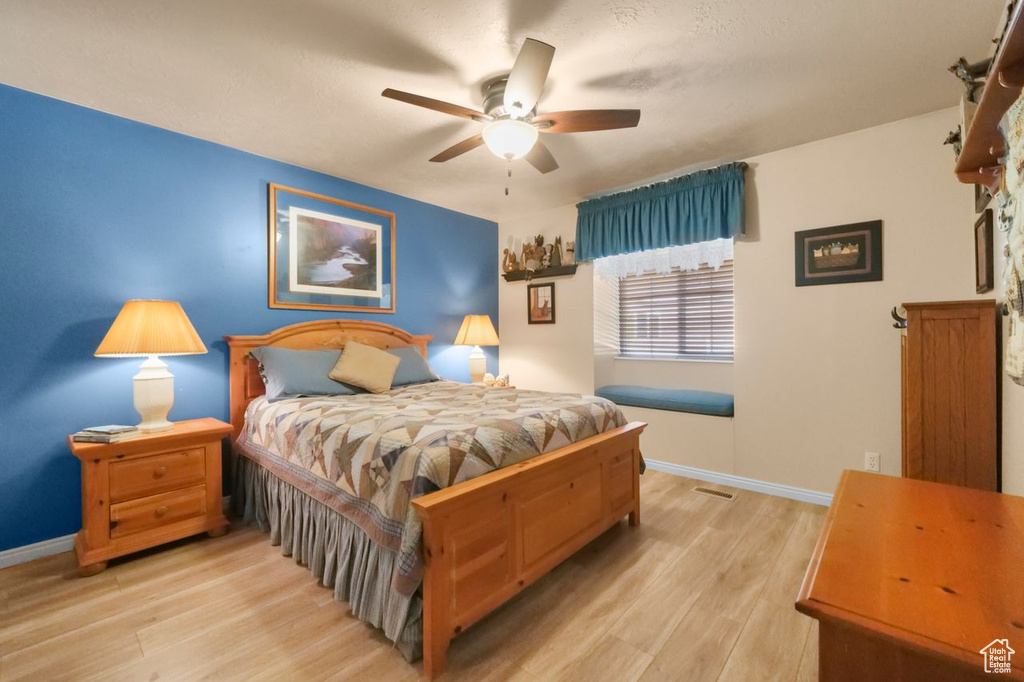 Bedroom featuring light wood-style floors, baseboards, and a ceiling fan