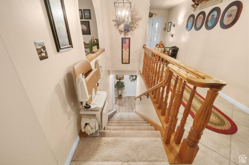 Stairway with baseboards, a chandelier, and tile patterned floors