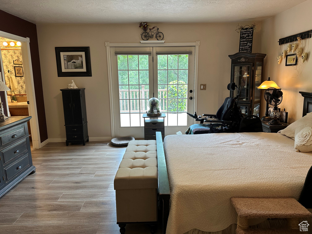 Bedroom with access to exterior, light wood-style floors, and baseboards