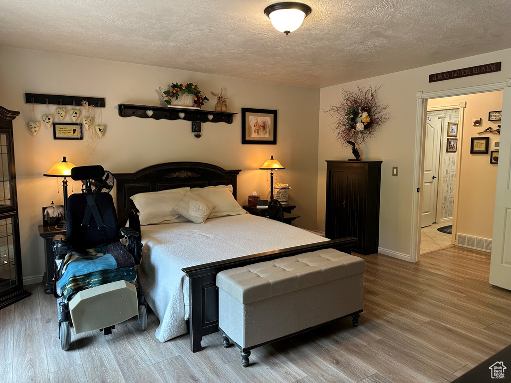Bedroom with a textured ceiling, wood finished floors, and baseboards