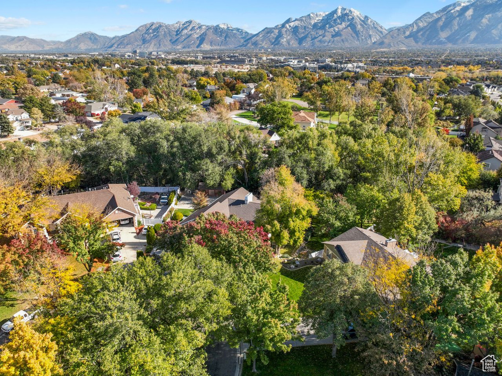Aerial view of property and surrounding area featuring a mountainous background and nearby suburban area