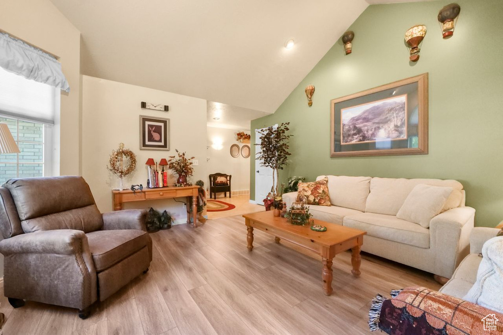 Living room featuring high vaulted ceiling, light wood-style floors, and recessed lighting