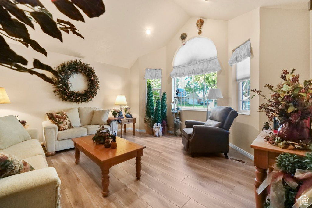 Living room featuring high vaulted ceiling, light wood-style floors, and baseboards