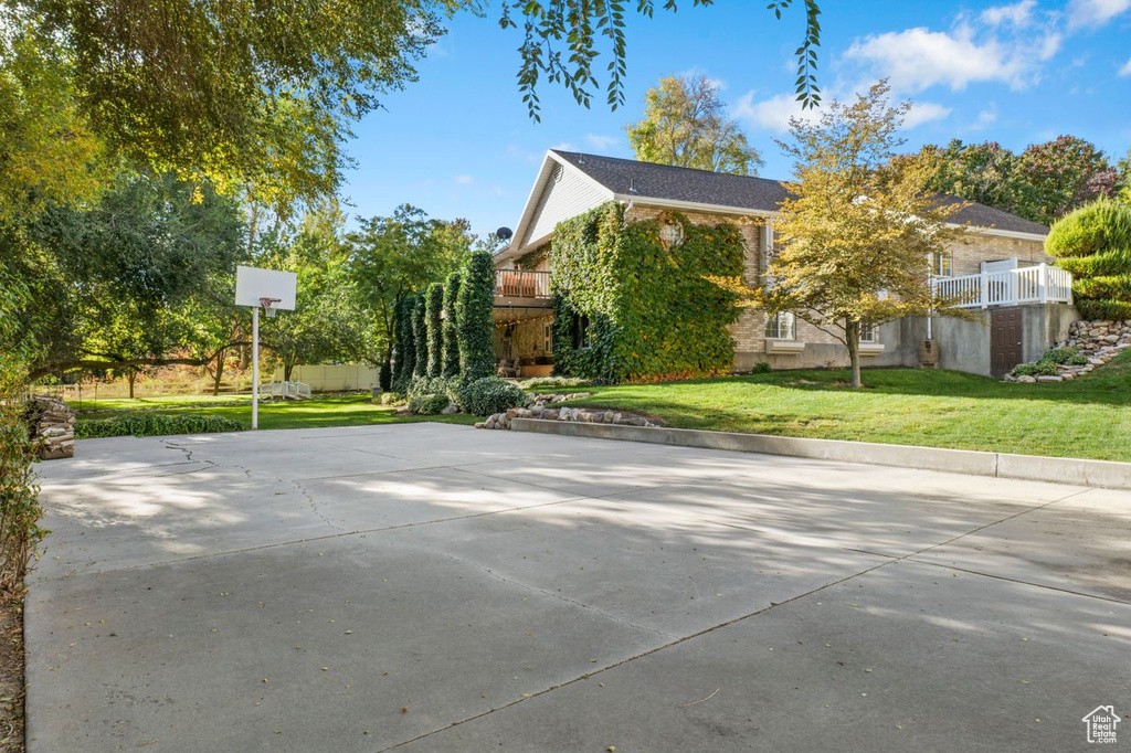 View of side of home with a lawn and basketball court