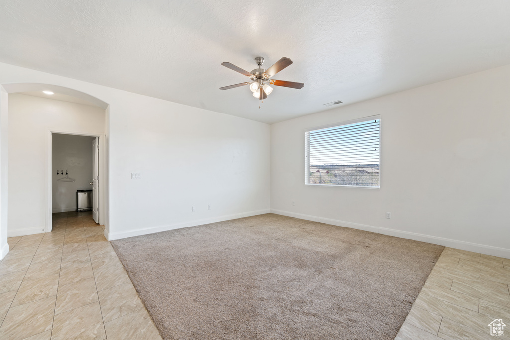 Empty room with arched walkways, a ceiling fan, and baseboards