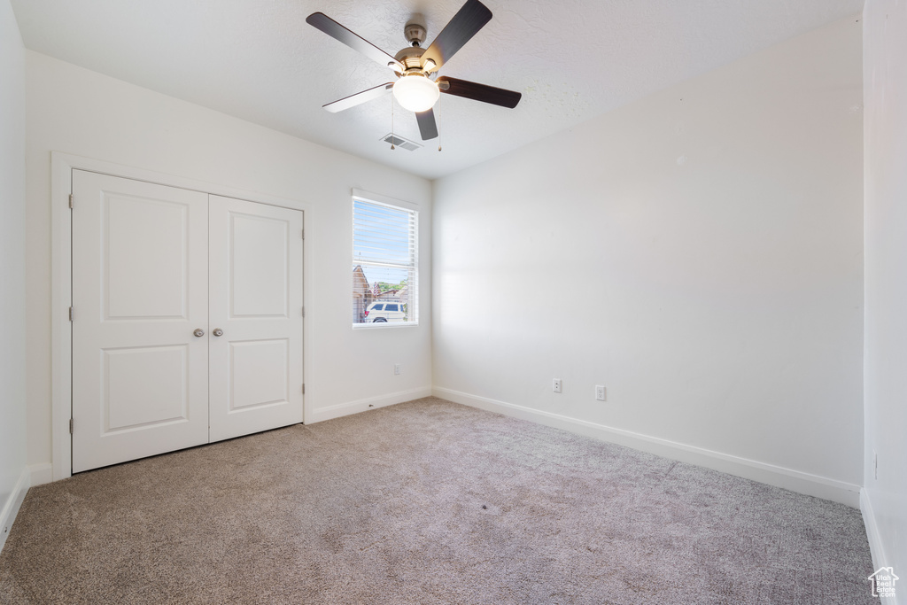 Unfurnished bedroom with carpet flooring, a closet, baseboards, and ceiling fan