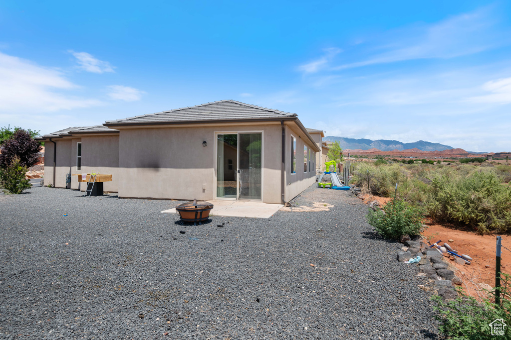 Back of house with a fire pit, a mountain view, stucco siding, a tiled roof, and a patio