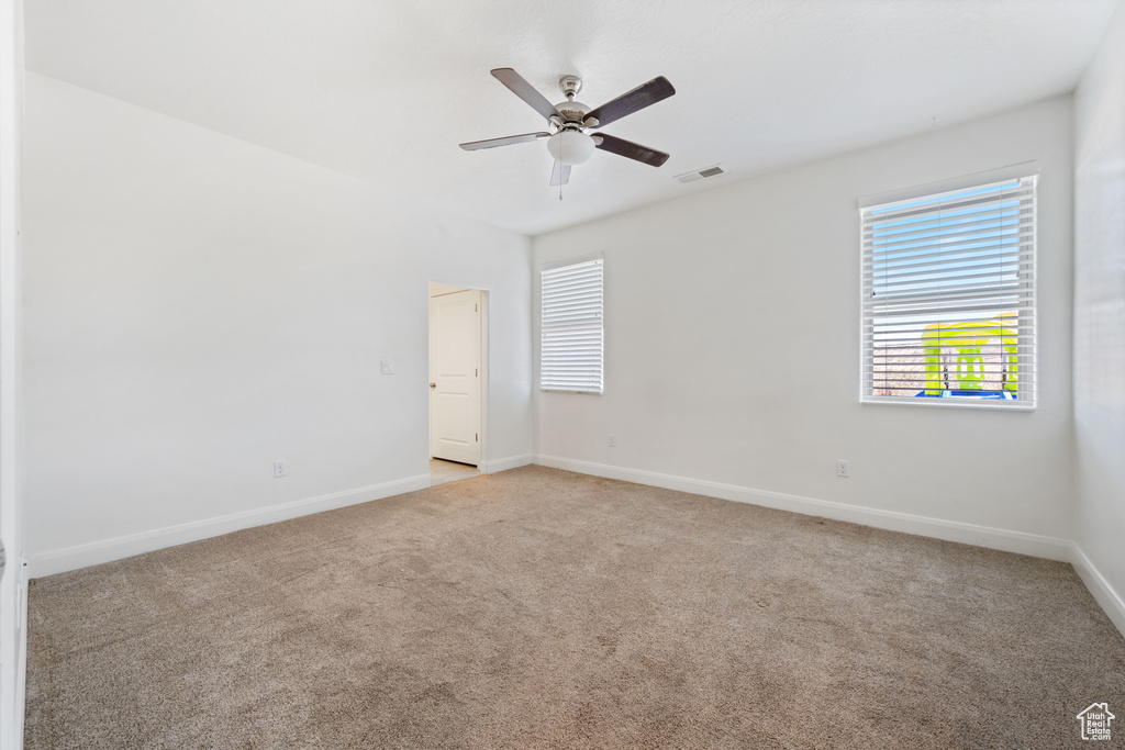 Empty room with light colored carpet, baseboards, and ceiling fan