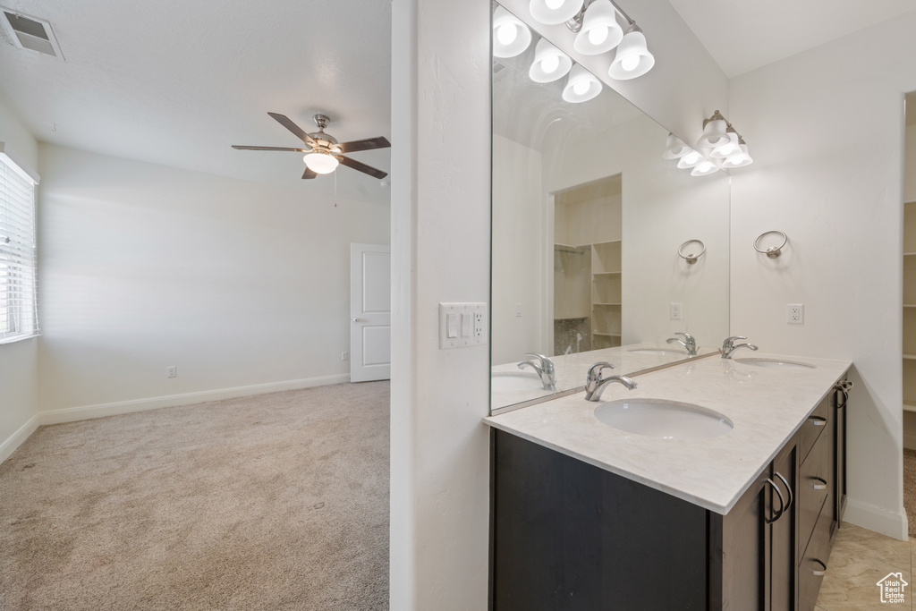 Full bath with ceiling fan, double vanity, and baseboards