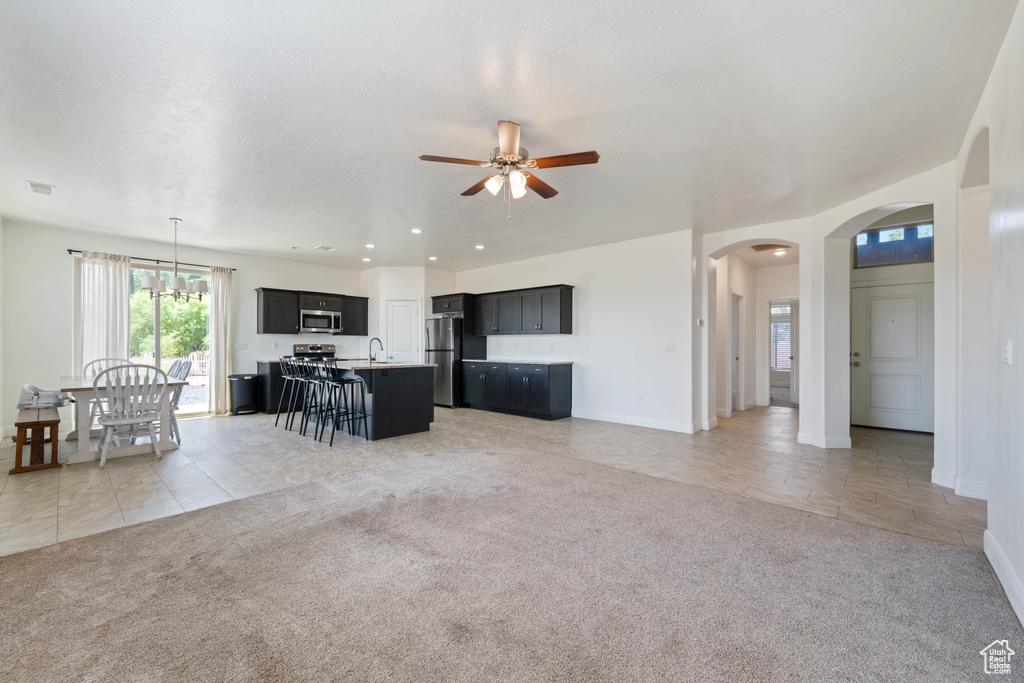 Living area with a ceiling fan, arched walkways, light carpet, and baseboards