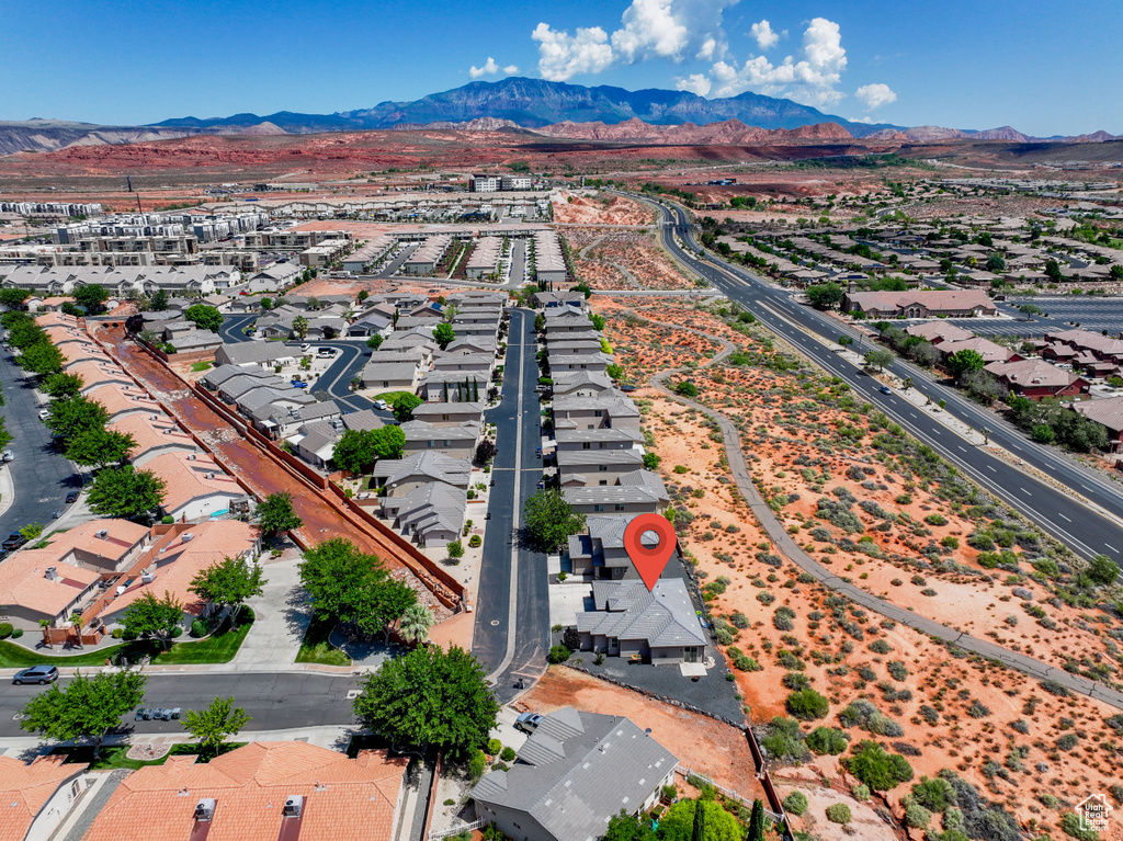 Aerial view of property and surrounding area featuring mountains and nearby suburban area