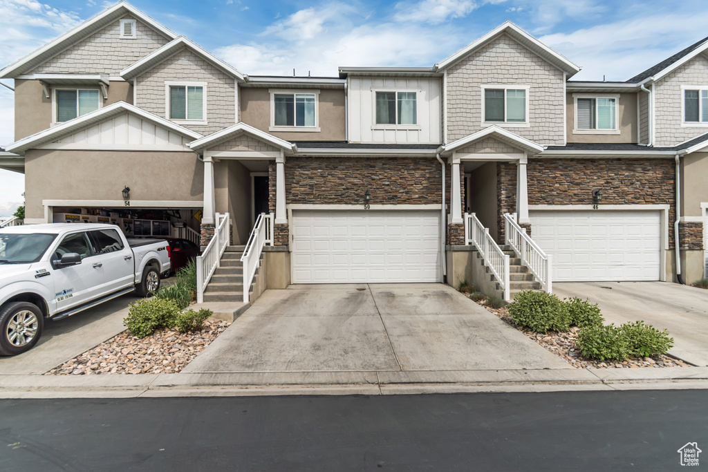 View of front facade with stone siding, a garage, board and batten siding, and concrete driveway