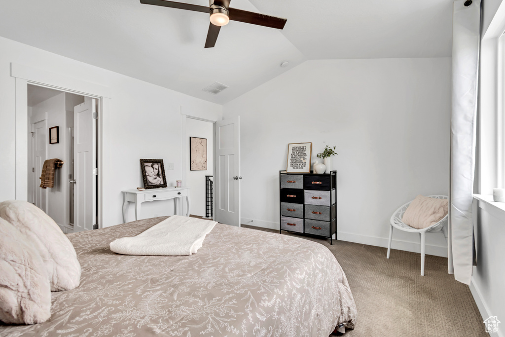 Carpeted bedroom with lofted ceiling, baseboards, and a ceiling fan