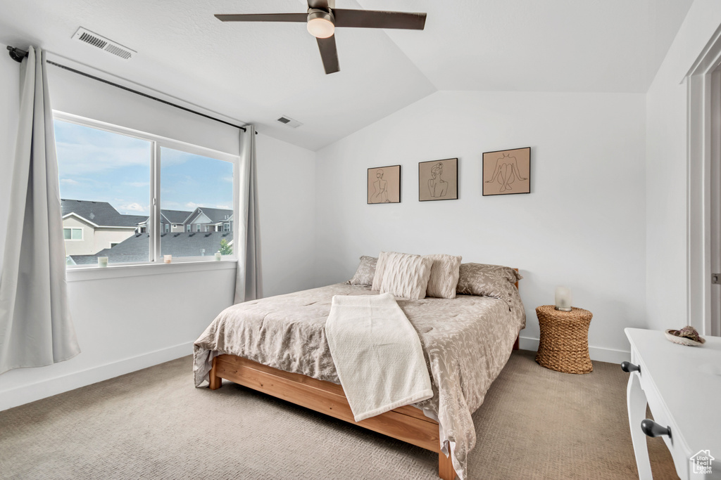 Bedroom with vaulted ceiling, carpet flooring, baseboards, and ceiling fan