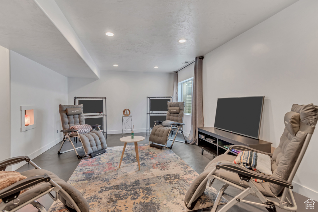 Living room featuring finished concrete flooring, recessed lighting, and baseboards