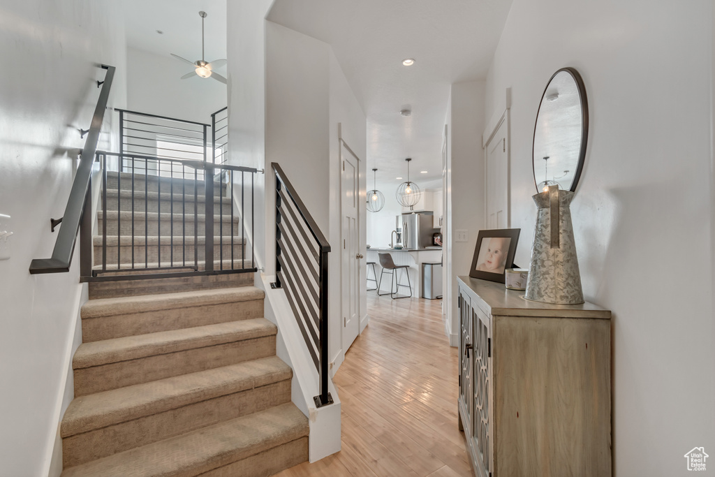 Stairs with ceiling fan, wood finished floors, and recessed lighting