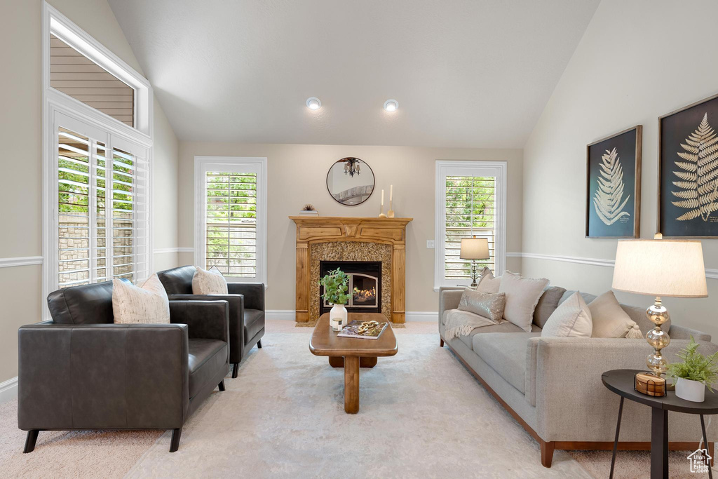 Living room with vaulted ceiling, carpet, plenty of natural light, and a high end fireplace