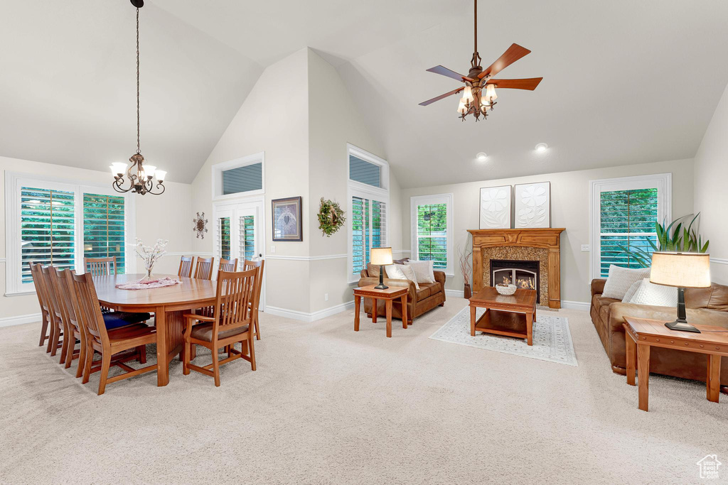 Dining space with a chandelier, a premium fireplace, light carpet, baseboards, and ceiling fan