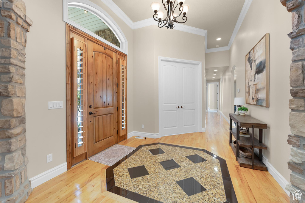 Foyer entrance featuring light wood finished floors, ornamental molding, a chandelier, and recessed lighting
