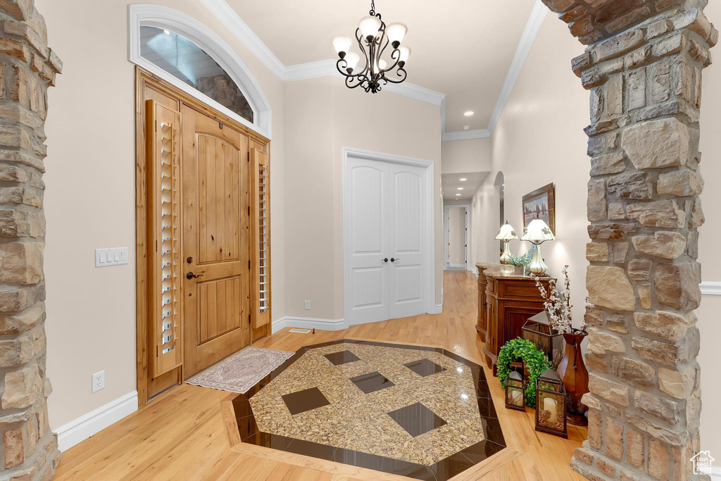 Foyer entrance with crown molding, light wood-type flooring, baseboards, a chandelier, and recessed lighting