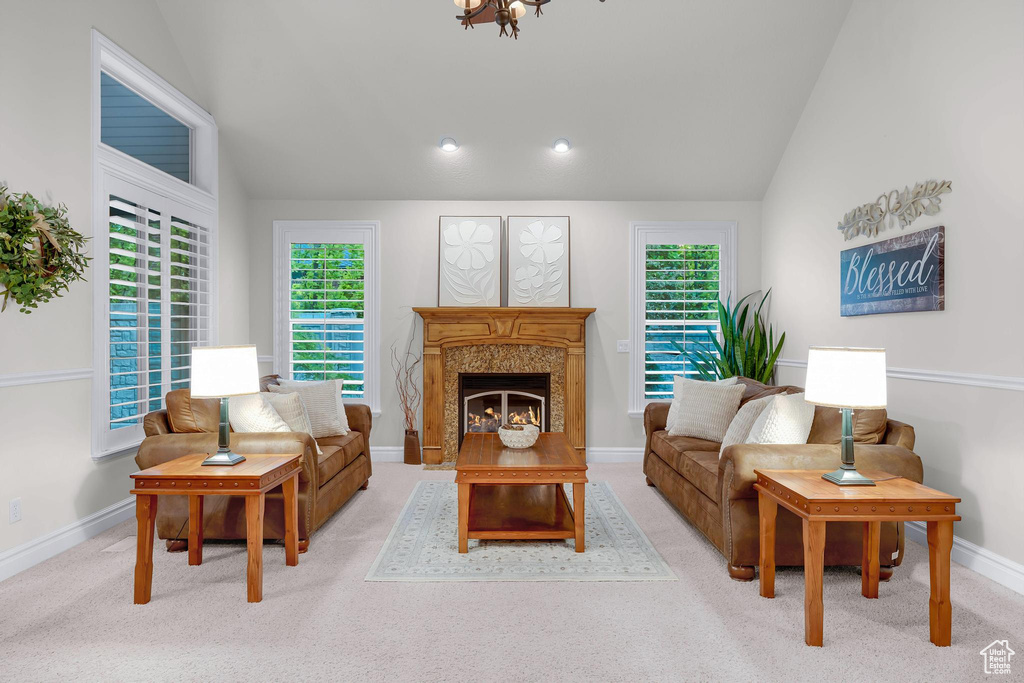 Carpeted living room featuring vaulted ceiling, baseboards, a high end fireplace, and healthy amount of natural light