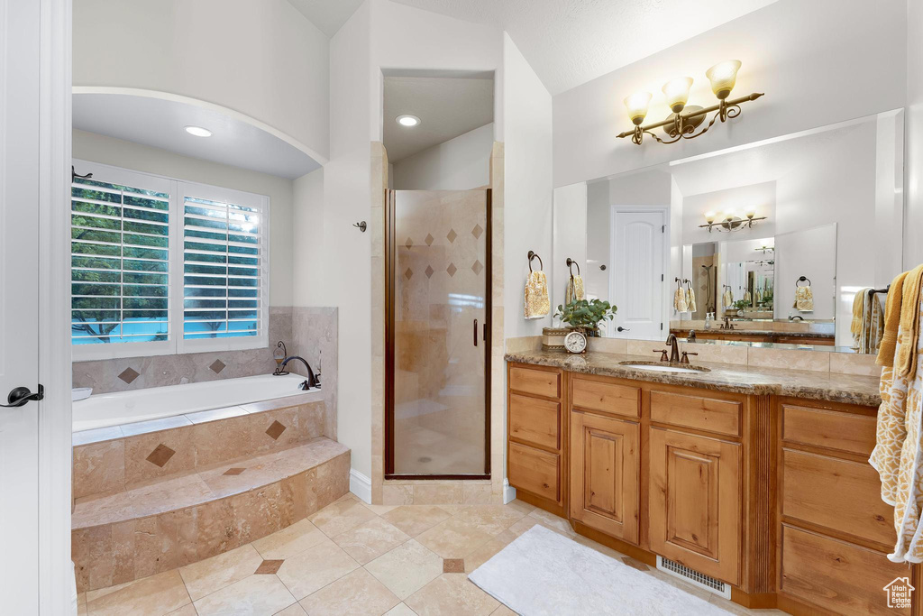 Full bath featuring a garden tub, vanity, a chandelier, a stall shower, and tile patterned floors