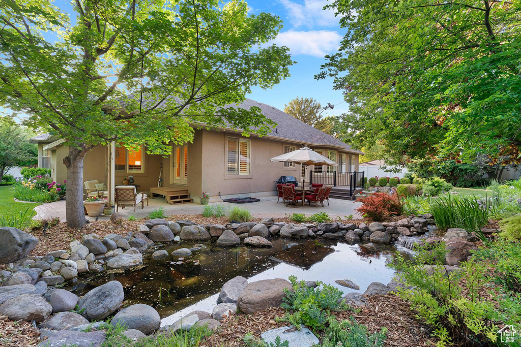 Back of property featuring a small pond, stucco siding, and a patio