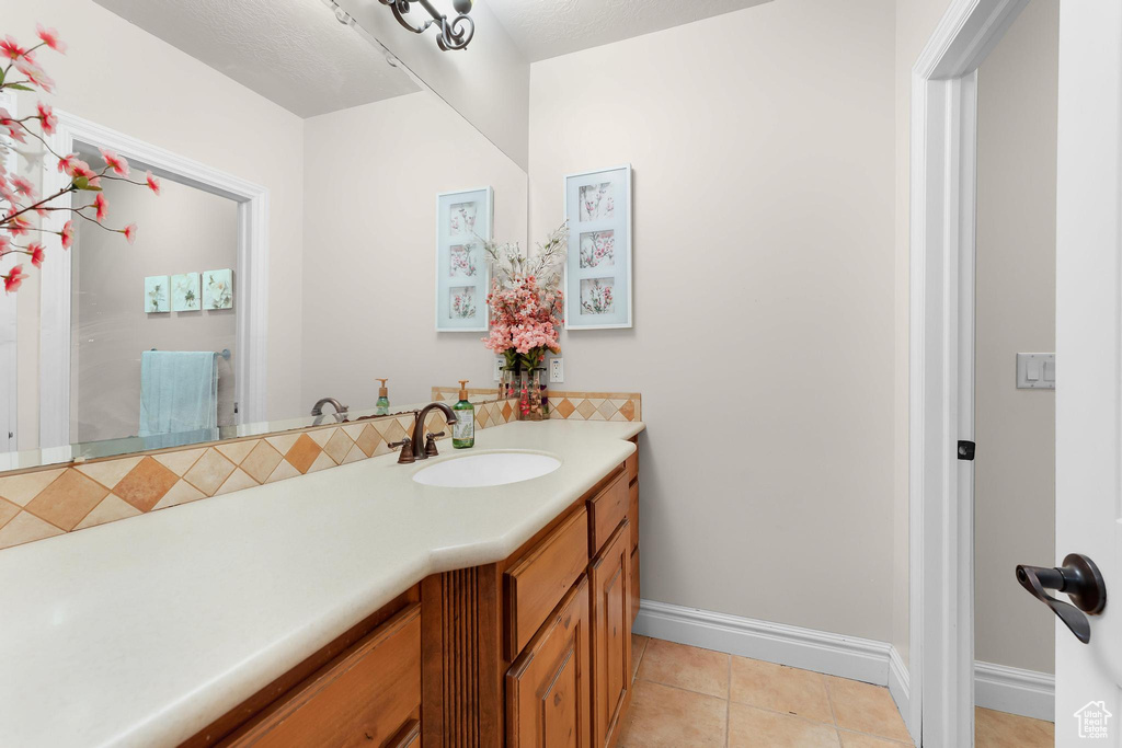 Bathroom with vanity, baseboards, tile patterned floors, and tasteful backsplash