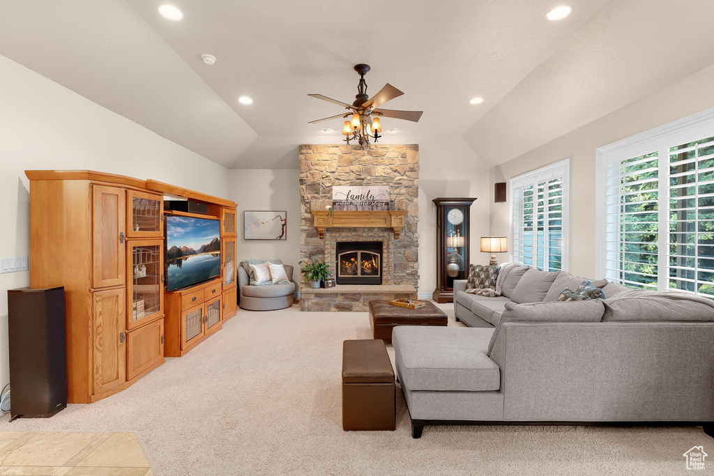 Living area with vaulted ceiling, a ceiling fan, light colored carpet, recessed lighting, and a stone fireplace