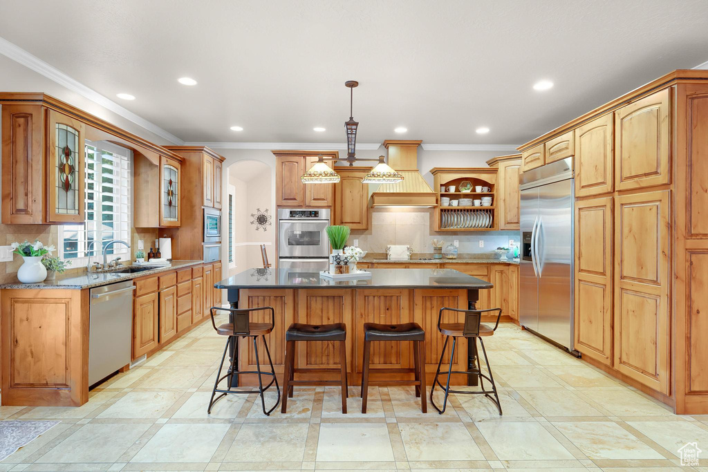 Kitchen featuring built in appliances, a sink, a center island, ornamental molding, and open shelves